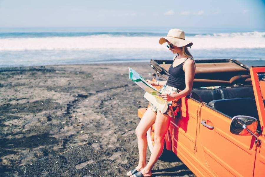 woman parked on beach looks at map