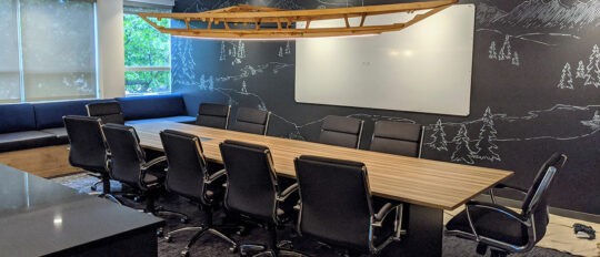 Empty Checkfront conference room with chalkboard walls, whiteboard, meeting table and chairs