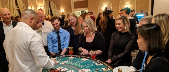 Checkfront employees gather around a poker table during a company casino night