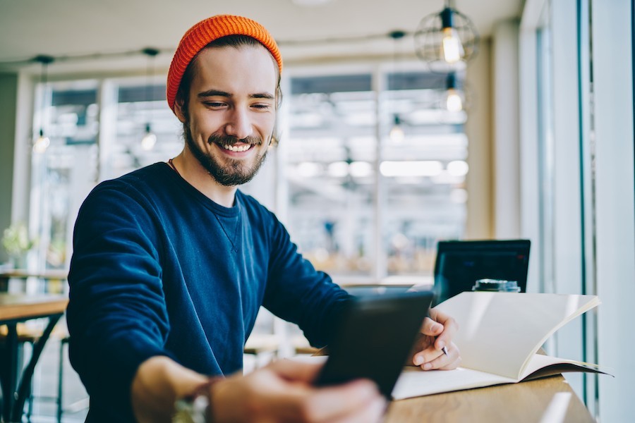 Happy hipster man smiling while reading email on his phone
