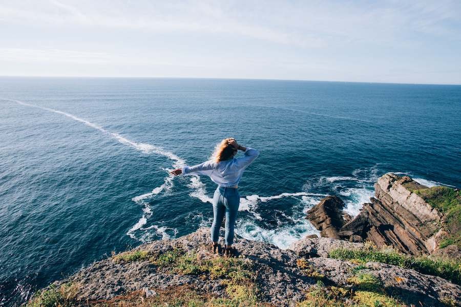 woman looking at ocean on cliffside