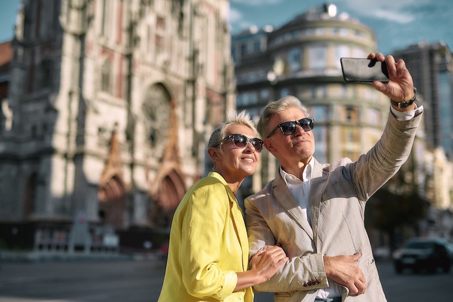An older couple taking a selfie shot in front of old church