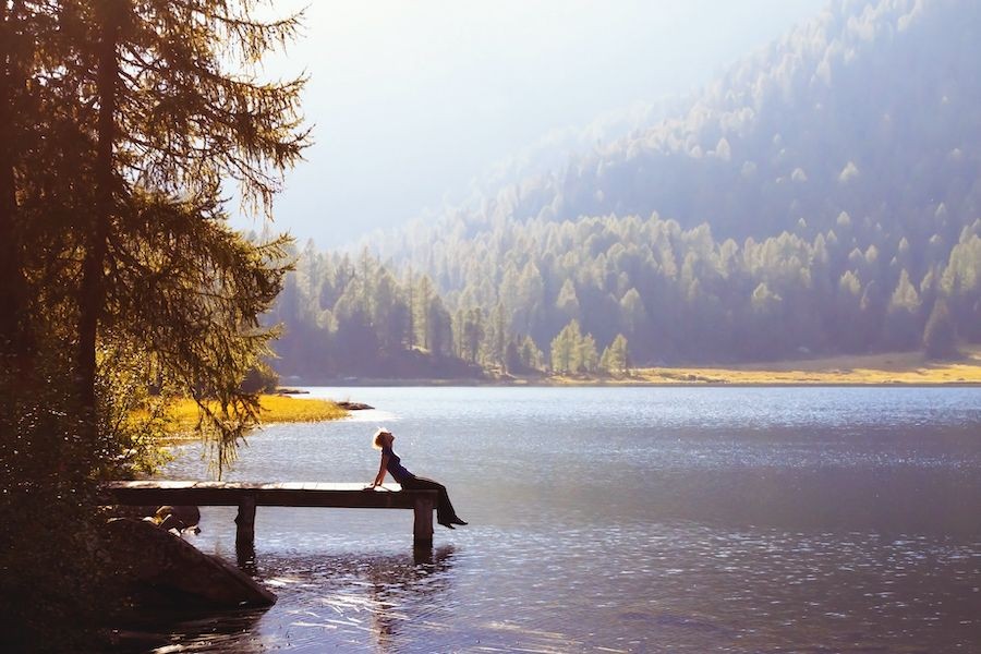 woman resting on a dock lakeside inspiring travel newsletter view