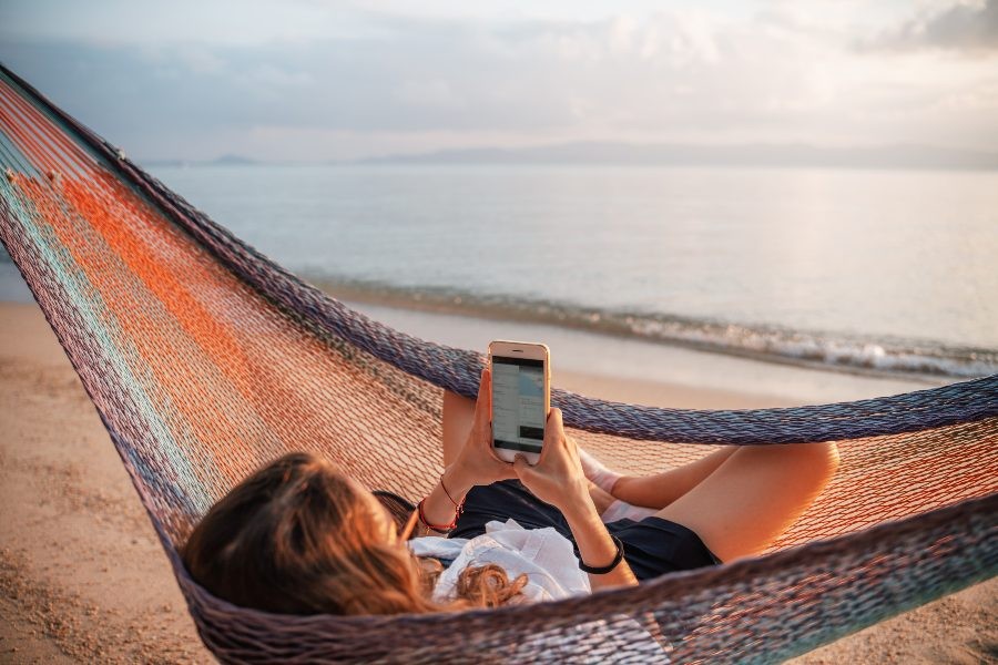 Girl in hammock looking at a reservation reminder email on phone