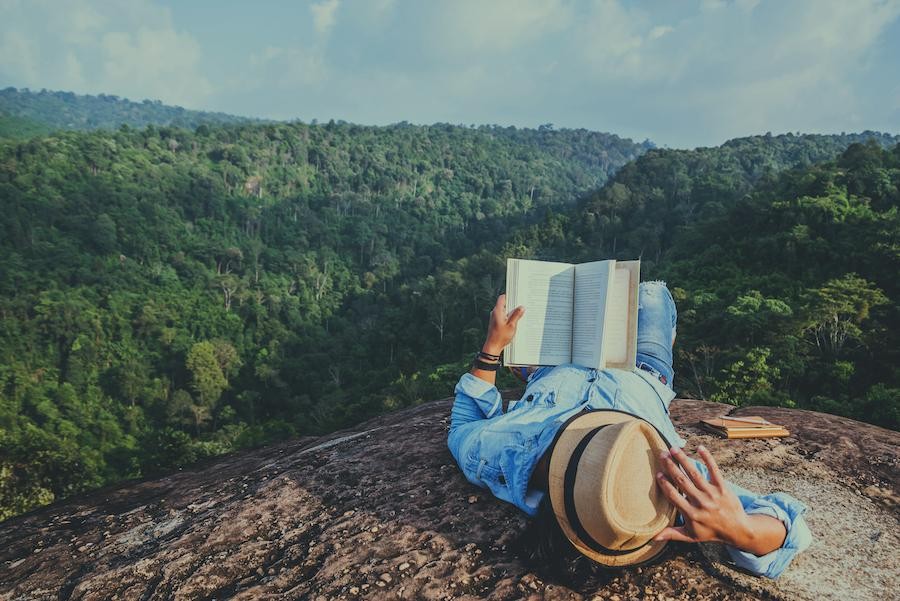 Person reading a book on a mountain