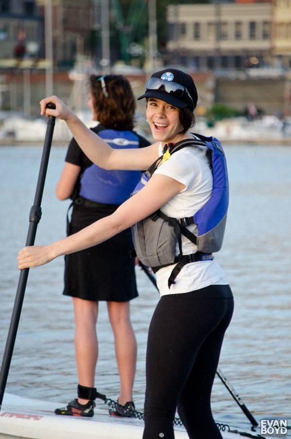Female stand up paddle boarder looking back smiling
