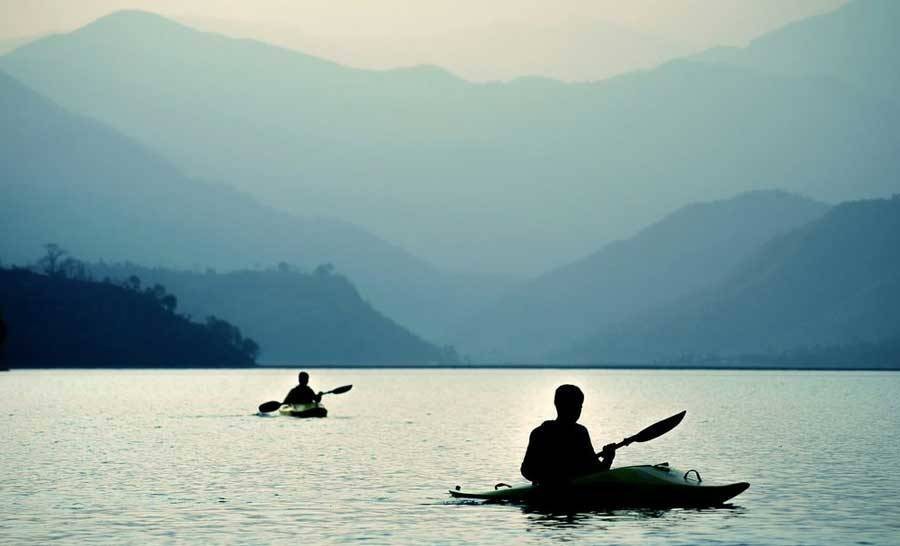 Two people kayaking on ocean with mountain scene