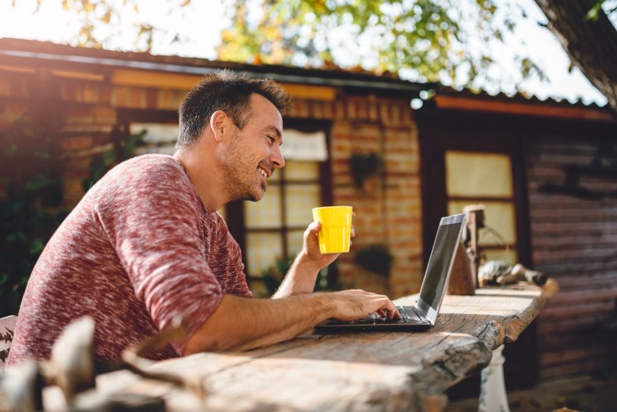 Smiling man at his computer with a  drink