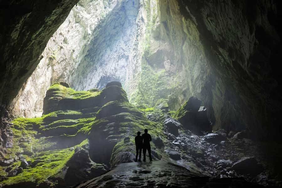 Two travelers standing in mossy cave in Iceland