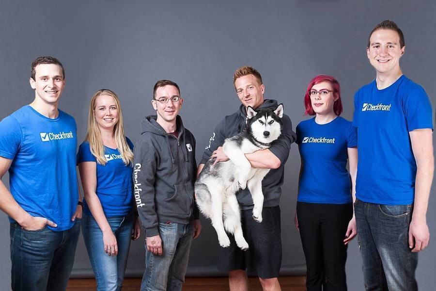 Group of Checkfront employees with Checkfront t-shirst on and holding pet husky