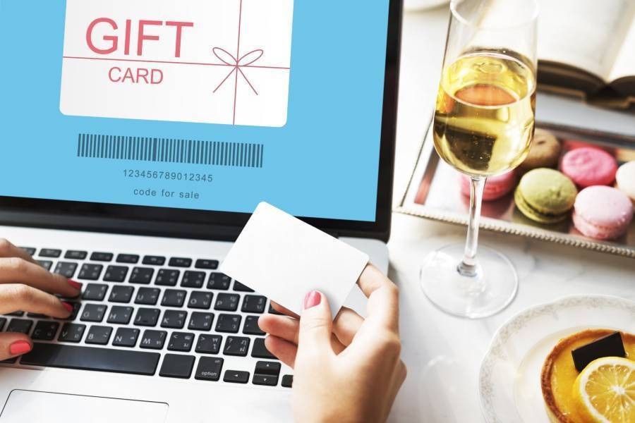 Shopper purchase digital gift card on laptop with wine and macarons