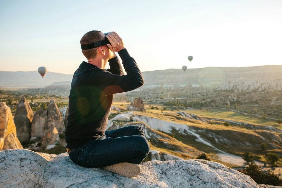 Recent online marketing trends of traveler using virtual reality headset while watching hot air balloons.