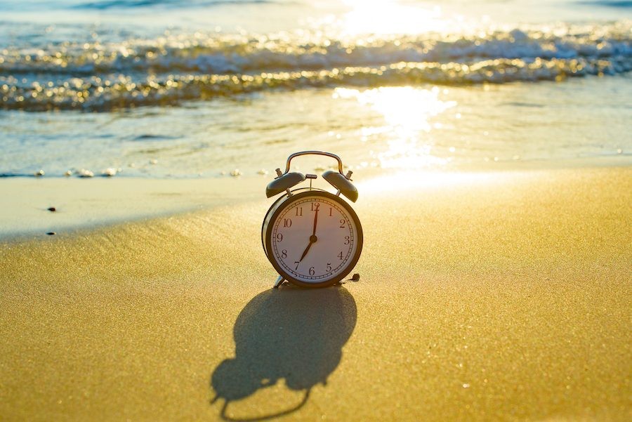 Clock on the beach at sunrise