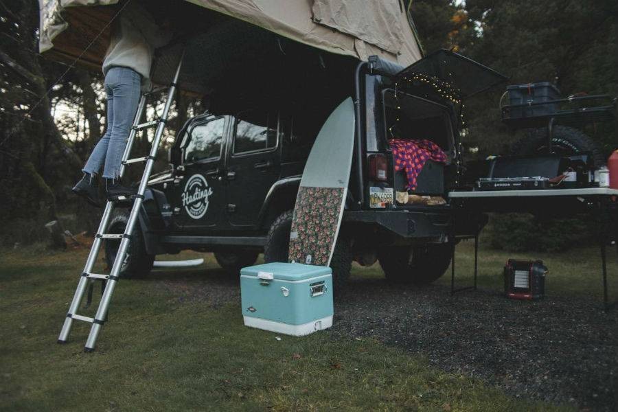 Hastings Overland guest climbing ladder into tent of camper Jeep.