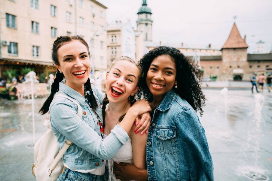 Three female travel friends posing in European street