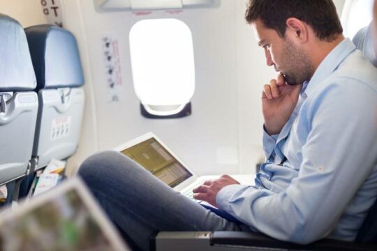 Perosn using a laptop on an aeroplane