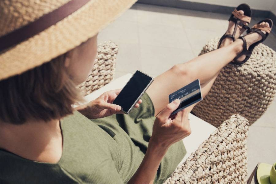 Woman sitting on a chair while holding a cell phone and credit card