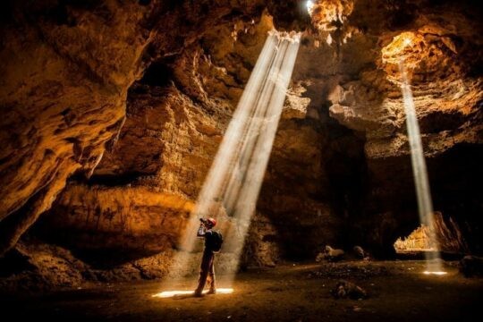 Person standing in a beam of light in a cave