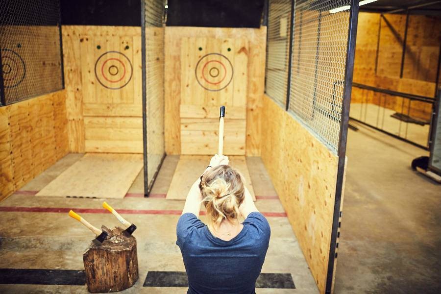 Woman about to throw an axe at a target in axe throwing business