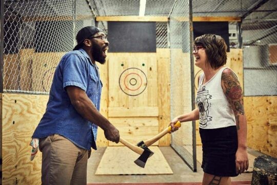 Man and woman standing with axes at axe throwing business
