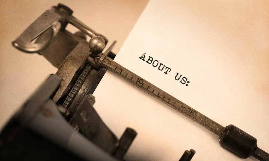 A typewriter with the words "About Us" typed out