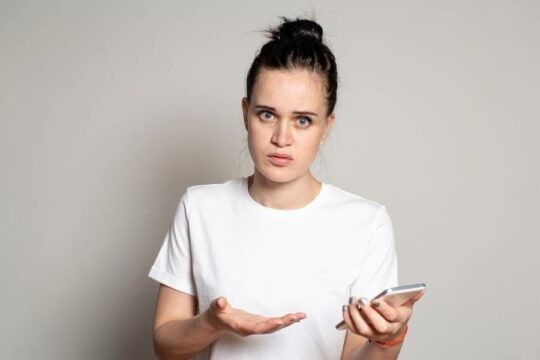 A distraught person motioning at their mobile device