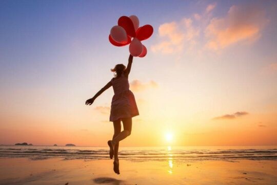 A woman on a beach holding balloons