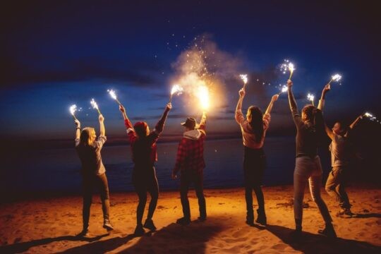 Group of people holding sparklers at the beach