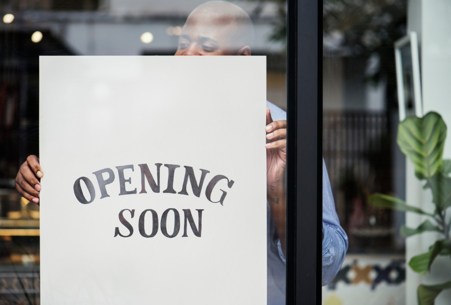 Shop owner holding an Opening Soon sign
