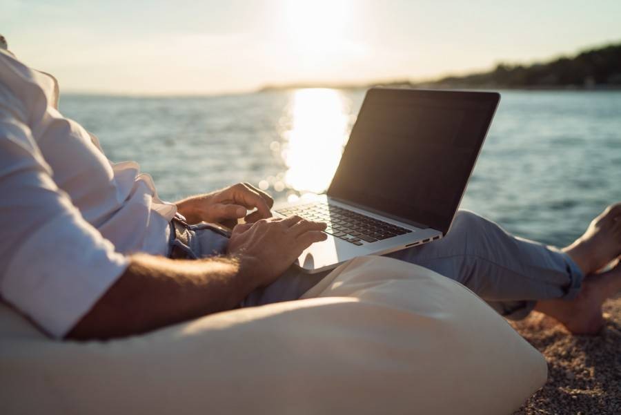 Person using a laptop at the ocean