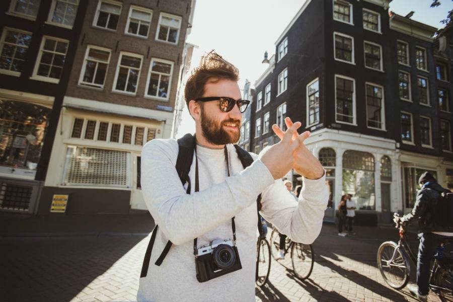 Male tourist doing Instagram hashtag symbol in courtyard while on tour in foreign city