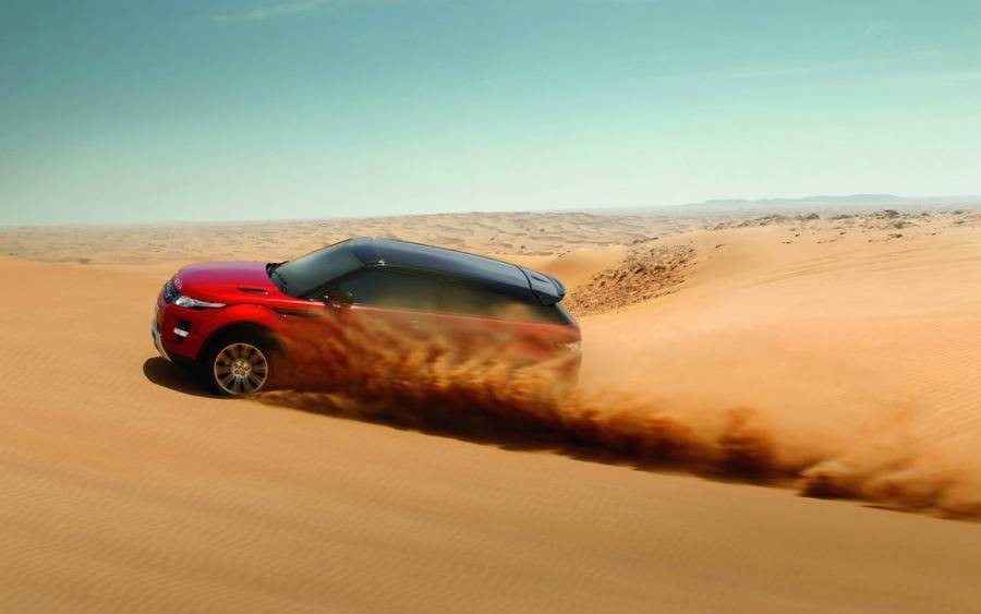 Red Land Rover driving through desert