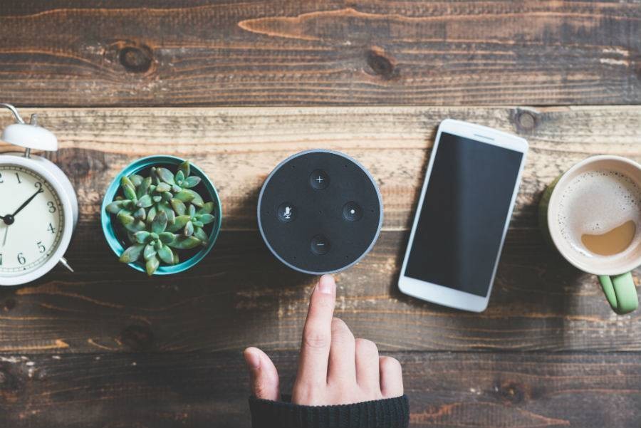 Smart speaker on table next to smartphone for traveler to use to find tours and activities.