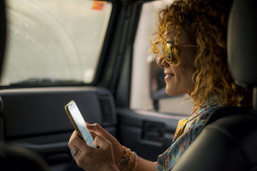 Curly haired woman checking social media in car