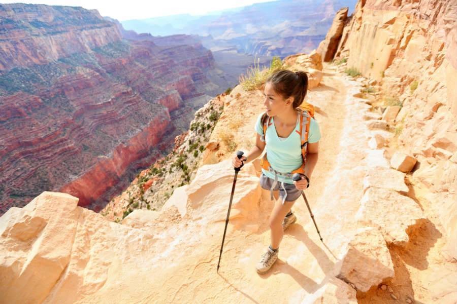 Google Mini on desk next to smartphone and journalAsian woman in blue shirt hiking in Grand Canyon with hiking poles