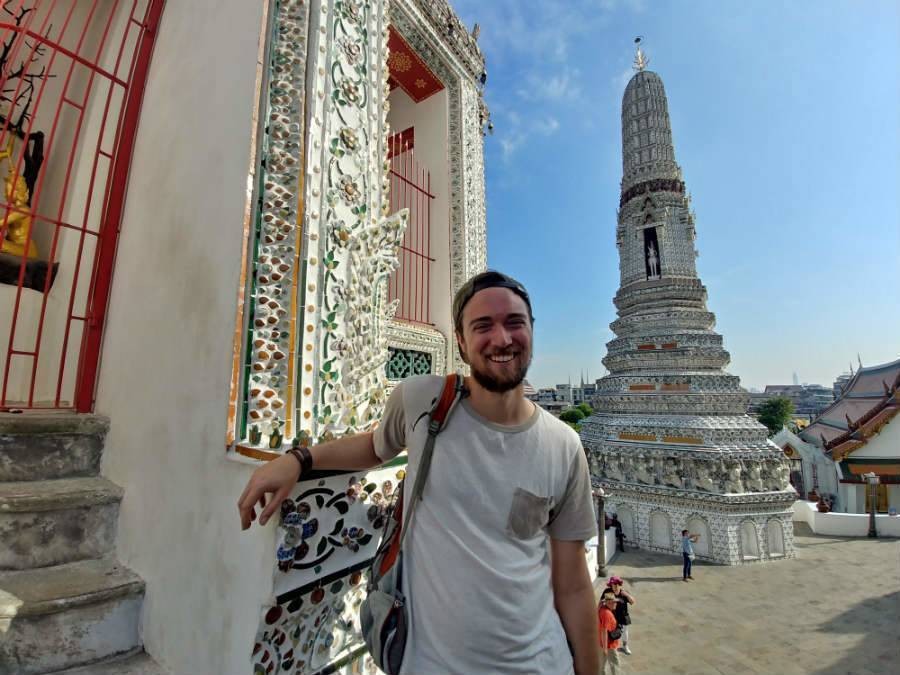 Male solo traveler touring around Thailand, posing in front of temple