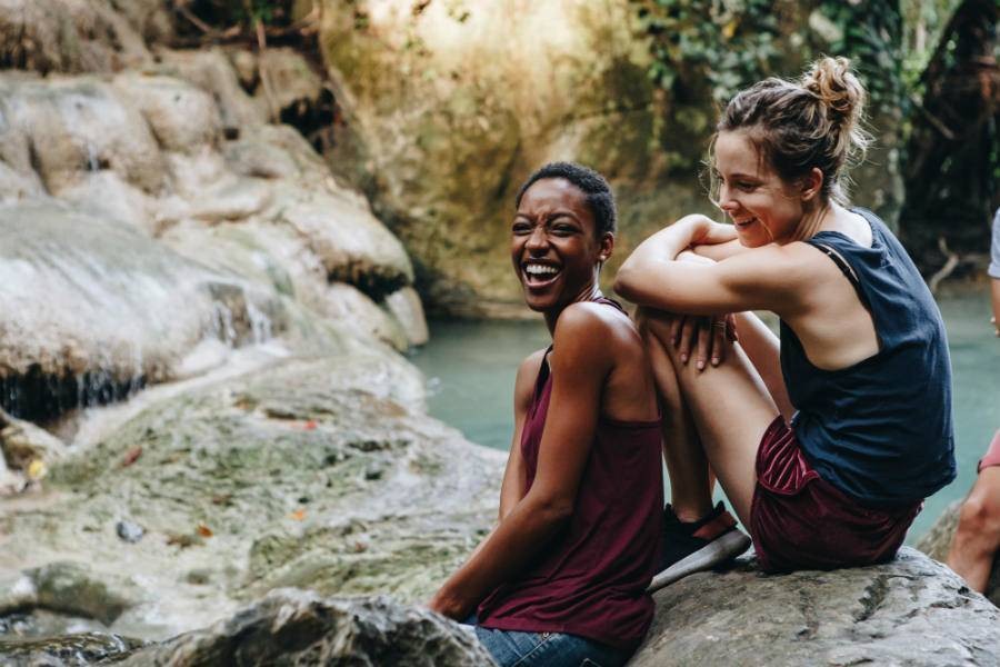 Two female travelers sitting at a waterfall in the jungle