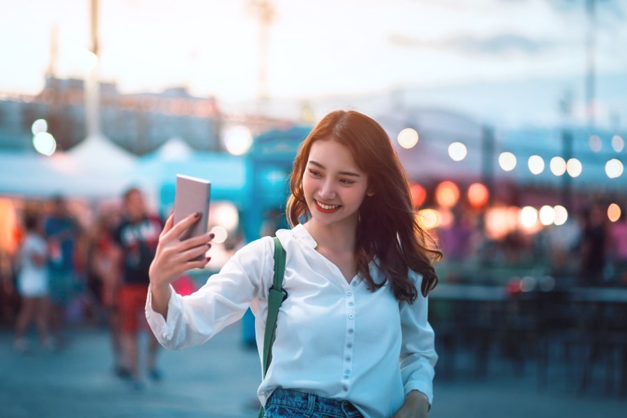 Young asian woman taking a TikTok video at an outdoor market