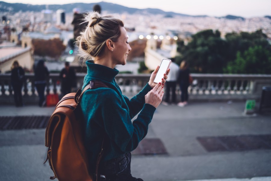 Young blonde female watching TikTok travel video while exploring European city