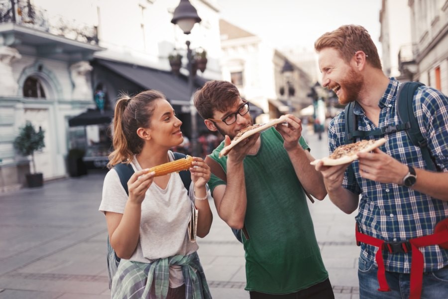 Three tour guides eating pizza on European street