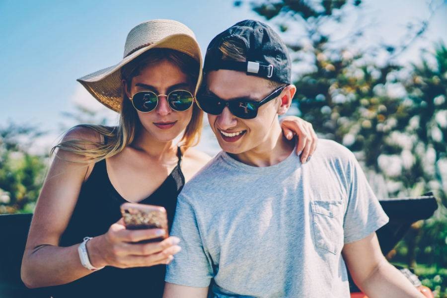 A female and male traveler looking at social media on smartphone.