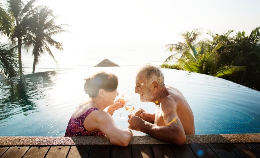 older adults lounging in a pool enjoy a moment at sunset