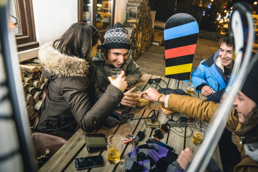 Four friends on a ski trip enjoying post-slope drinks together