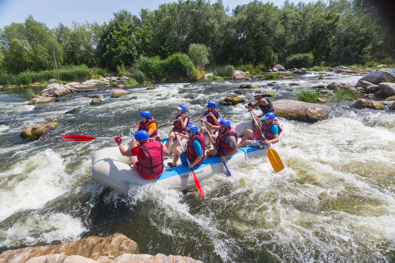 group of 8 adults whitewater rafting on rapids